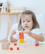 A child playing with the PlanToys Fractions Cubes. They are creating a stack. 