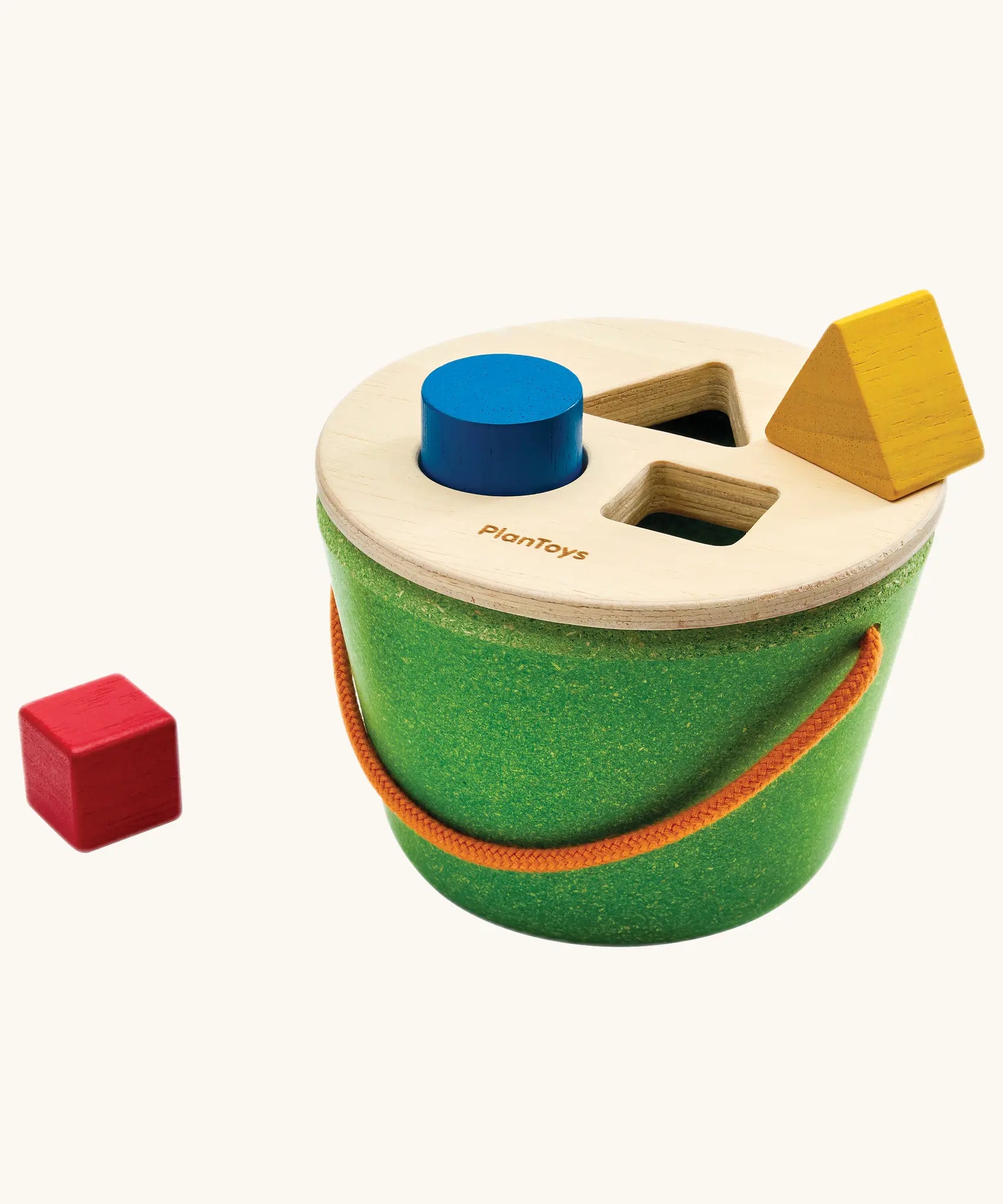 Close-up of a toddler's hand fitting the blue cylinder into the bucket lid