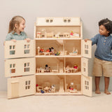 Children playing with the PlanToys Grand Victorian Dollhouse. Door shown open and all floors and attic room has PlanToys dolls house furniture inside.