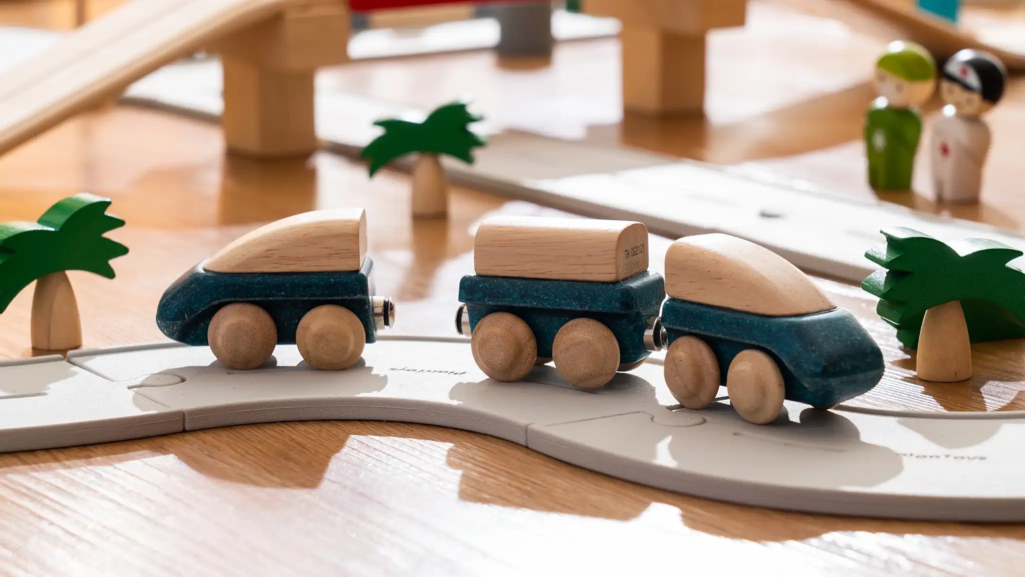 PlanToys blue wooden hybrid train, three carriage train with magnetic connections placed on the rubber road.