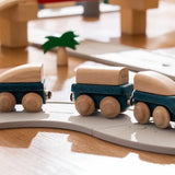 PlanToys blue wooden hybrid train, three carriage train with magnetic connections placed on the rubber road.
