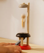 A close up of a child's hand playing with the PlanToys Natural Rubberwood Jumping Acrobat Toy. PlanToys have a vast range of sustainable wooden toys are available at Babipur.