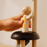 A close up of a child's hand placing the acrobat figure on the PlanToys Natural Rubberwood Jumping Acrobat Toy. PlanToys have a vast range of sustainable wooden toys are available at Babipur.