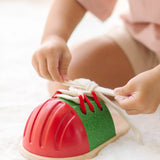 Child tying the laces on the PlanToys life size tie-up wooden shoe toy. 