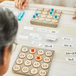 A close up of the PlanToys Maths Bingo Game being played on a table. 
