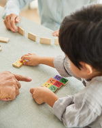 Close up of young boy putting down a piece of the PlanToys mood dominos set on a table