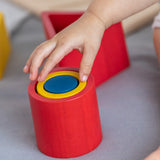 Close up of young child making a stack with the PlanToys matching and nesting shapes on a grey bed
