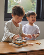 Two boys playing with the PlanToys plastic-free wooden orchard shape sorting toy on a wooden table