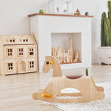 PlanToys childrens wooden Palomino rocking horse on a white fluffy rug in front of a fireplace and Victorian dollhouse