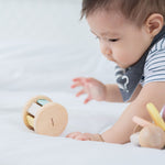 A baby crawling towards a PlanToys Pastel Roller. 