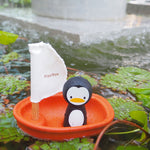 A PlanToys Penguin Sailing Boat on a pond. 