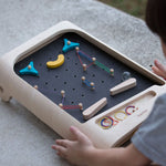 A close up of a child playing with the PlanToys pinball wooden toy game. 