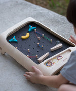 A close up of a child playing with the PlanToys pinball wooden toy game. 