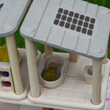 An overhead angle view of the PlanToys PlanSpace bathroom set attached to the other sets from the PlanSpace collection. The solar panel details on the roof can be seen and a green coloured Nin peg doll has been placed laying down in the bath. 