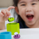 A close up of a child placing the green bee from the Plan Toys Bee Hives Rainbow set into the green hive. 