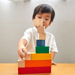 Young boy making a stack with the PlanToys wooden rainbow counting cubes