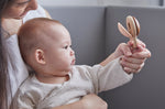 Close up of mother and baby holding the PlanToys wooden Shake N Clap baby rattle toy