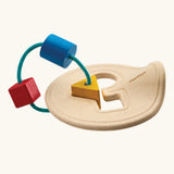 Toddler holding up the wooden shape sorter to inspect the pieces