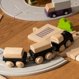 PlanToys black wooden classic toy train placed on rubber train tracks and wooden roads.