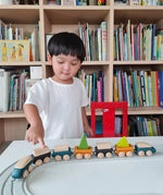 Child playing with PlanToys blue wooden trains on a rubber railway tracks. 