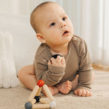 A baby holding the ball from the PlanToys high contrast Triangle baby Clutching Toy. A black and natural wood wooden ball in a stretchy triangle clutching toy. PlanToys range of toys are made from sustainably sourced rubberwood, we're proud stockists of PlanToys here at Babipur. 