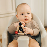 A baby playing with the PlanToys high contrast Triangle baby Clutching Toy. A black and natural wood wooden ball in a stretchy triangle clutching toy. PlanToys range of toys are made from sustainably sourced rubberwood, we're proud stockists of PlanToys here at Babipur. 