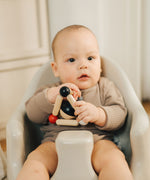 A baby playing with the PlanToys high contrast Triangle baby Clutching Toy. A black and natural wood wooden ball in a stretchy triangle clutching toy. PlanToys range of toys are made from sustainably sourced rubberwood, we're proud stockists of PlanToys here at Babipur. 