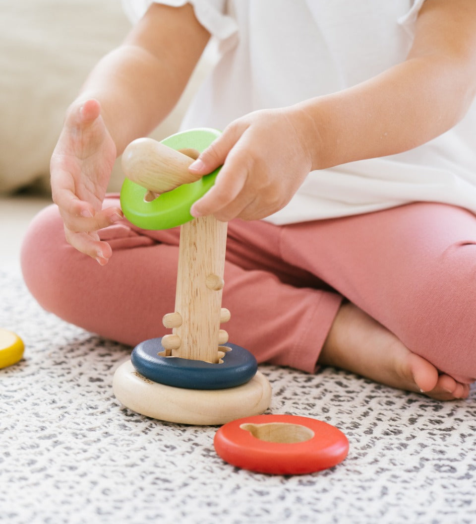 Close up of child's hands sliding green disc onto the PlanToys twist and sort game