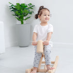 Toddler sat on the wooden foldable rocking horse by PlanToys. Side view.