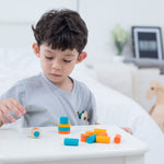 A child playing with the PlanToys mini stacking game on a small table.