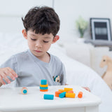 A child playing with the PlanToys mini stacking game on a small table.
