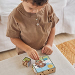 Close up of boy stacking the Waldorf PlanToys animal puzzle toy blocks on a beige cushion