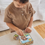 Close up of boy stacking the Waldorf PlanToys animal puzzle toy blocks on a beige cushion