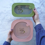 A green poco small reusable wipes container next to a pink grande container in a person's hands.