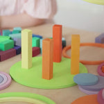 A video of children using the Grimm's concentric circles to play in all sorts of ways. First they stack a tower with wooden building blocks, then they spin the disc circles on the table, then they create steps and run the circles down.