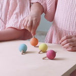 A video of children spinning the Grimm's pastel rainbow traditional wooden spinning tops. 