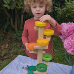 child playing with the Beck wooden marble run with xylophone at the end. Balls fall and the spin around a number of wooden pieces, then drop onto a xylophone. 