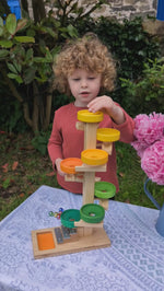 child playing with the Beck wooden marble run with xylophone at the end. Balls fall and the spin around a number of wooden pieces, then drop onto a xylophone. 