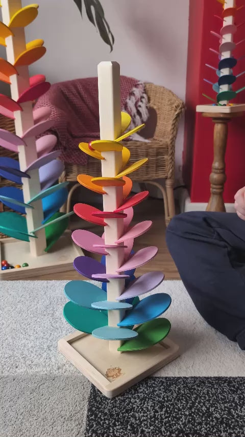 Small Magic Wood Marble Tree, a wooden Ball Run with rainbow coloured leaves, being played with by a child.