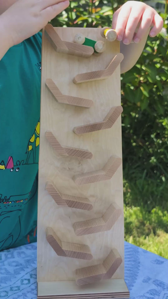 A video of the wooden Beck Cascading ‘Tower Running Track’ with Race Cars in action, filmed outdoors in the Babipur garden. Small wooden cars race down a series of sloped wooden tracks, flipping from one level to the next
