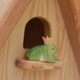An Ostheimer frog prince wooden toy figure placed on the perch at the top of the Ostheimer fairy tale dolls house. This wooden figure is part of a large range of expertly hand crafted, Waldorf inspired, wooden toys here at Babipur. 