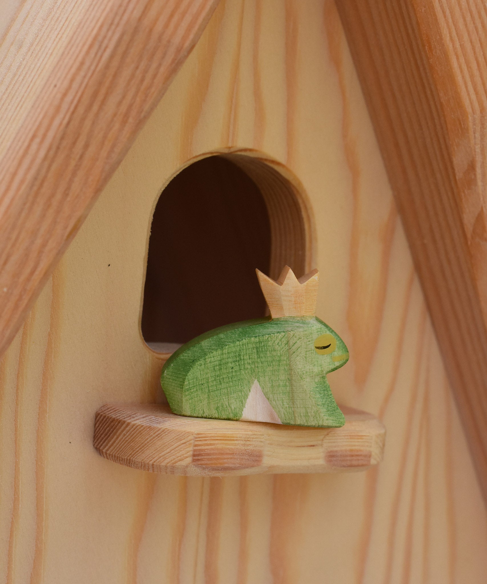 An Ostheimer frog prince wooden toy figure placed on the perch at the top of the Ostheimer fairy tale dolls house. This wooden figure is part of a large range of expertly hand crafted, Waldorf inspired, wooden toys here at Babipur. 