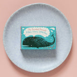 The Printed Peanut aloe vera natural handmade soap bar in a decorative cardboard packaging box placed on a light blue circular dish.