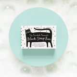 The Printed Peanut Black Cat charcoal soap gift box displayed on blue background with bubbles, natural soap with rosemary and lime.
