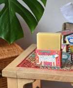 Printed peanut ylang ylang natural soap bar placed on top of the red decorative cardboard packaging box with dalmatian style dog illustration.