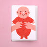 The Printed Peanut new baby greeting card with baby in red outfit, illustrated mini new baby card displayed on pink background
