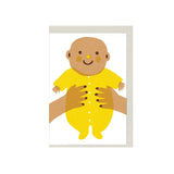 Illustrated new baby greeting card with smiling baby in yellow outfit, held by hands, mini A7 gift card by The Printed Peanut