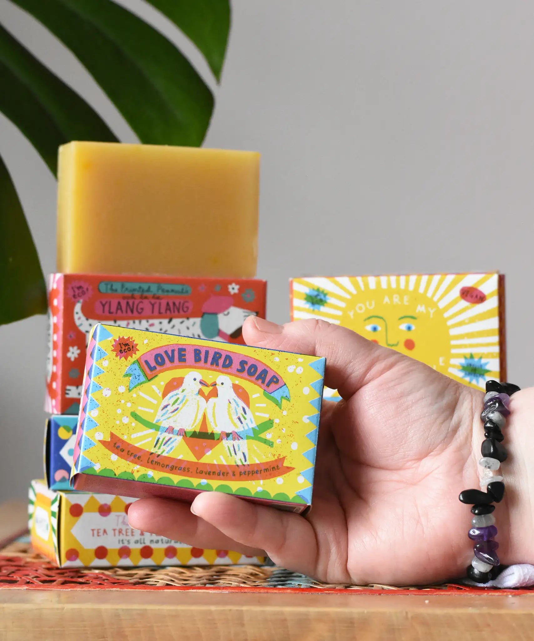 Printed Peanut tea tree, lemongrass, lavender and peppermint soap bar in a love bird themed illustrated box. Other Printed Peanut soaps can be seen stacked in the background.