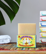 Printed Peanut tea tree, lemongrass, lavender and peppermint soap bar in a love bird themed illustrated box. The natural soap bar has been placed on top of the cardboard packaging box.