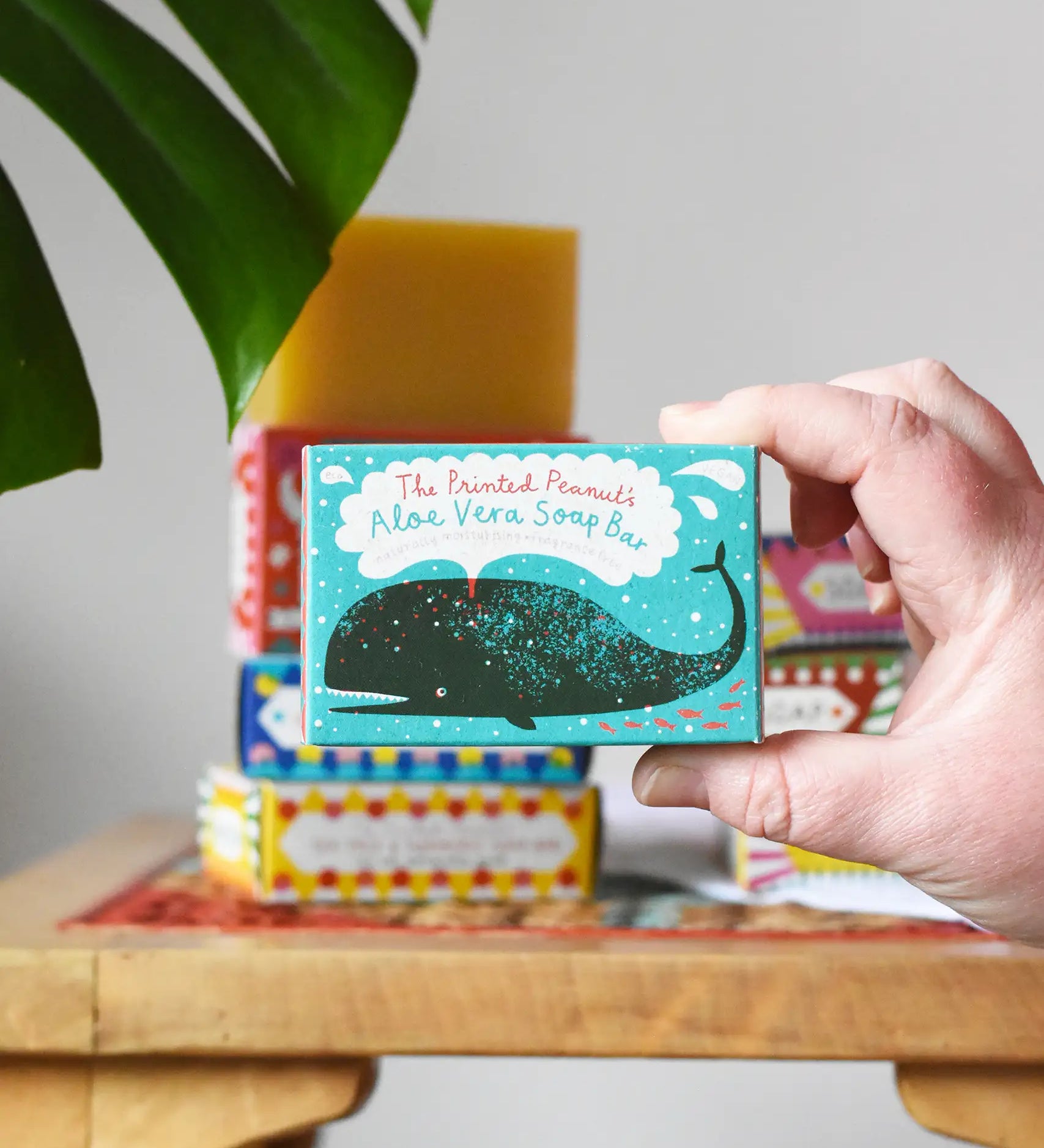 Close up of the Printed Peanut aloe vera fragrance free natural handmade soap bar in a decorative blue cardboard box showing a whale illustration in an adult's hand.